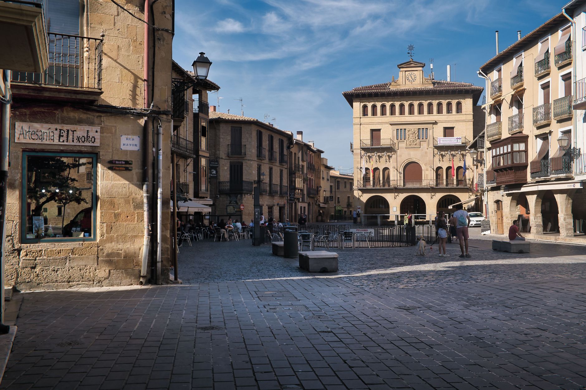 Plaza soleada de un pueblo español con palmeras y terrazas