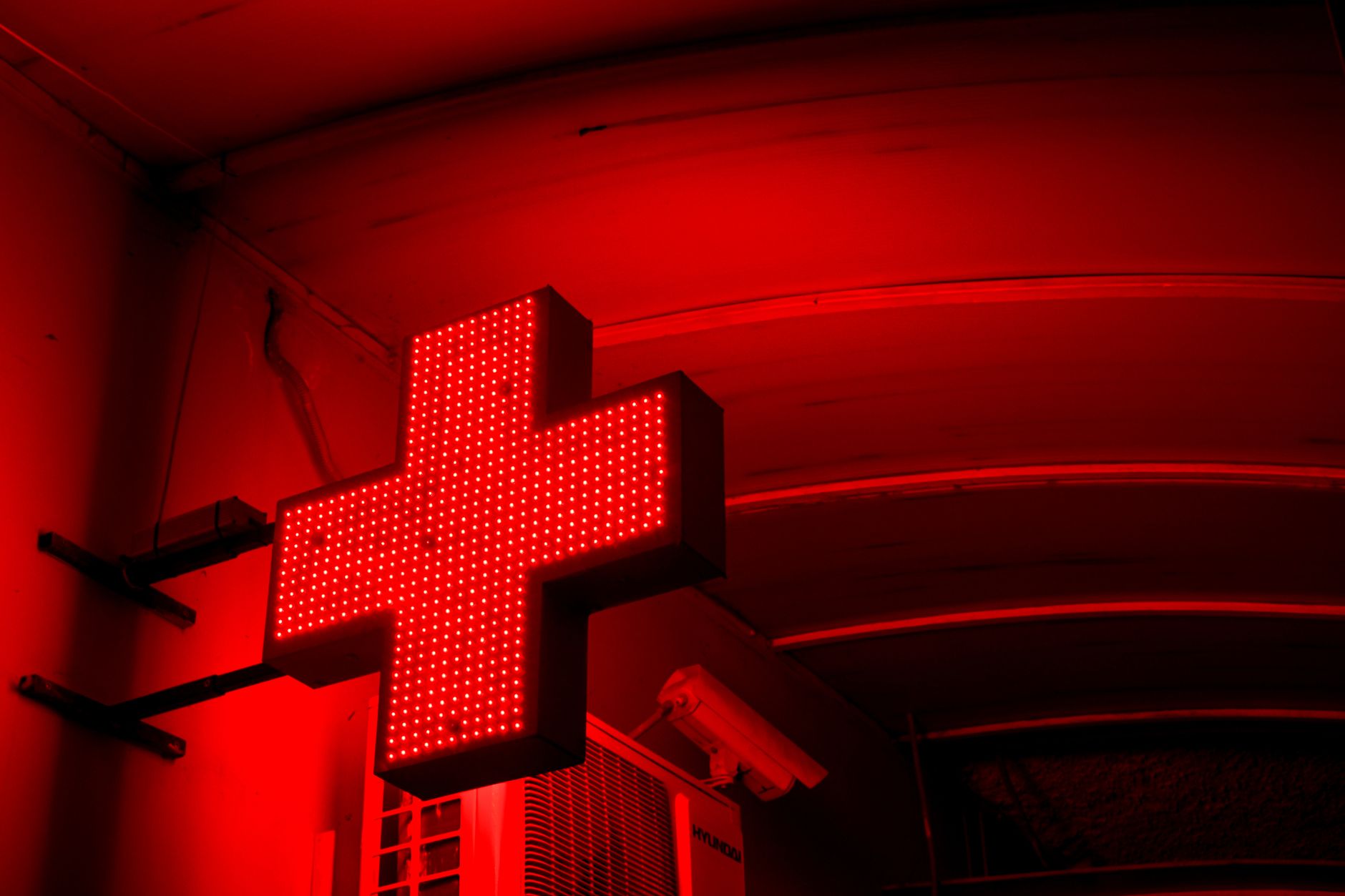 Cruz verde de farmacia iluminada de noche, señal de farmacia de guardia abierta