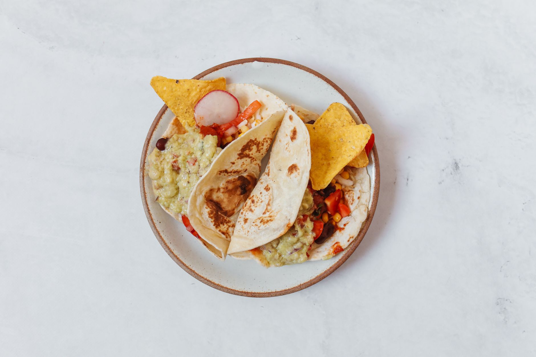 Tacos al pastor y nachos con guacamole en mesa de restaurante mexicano