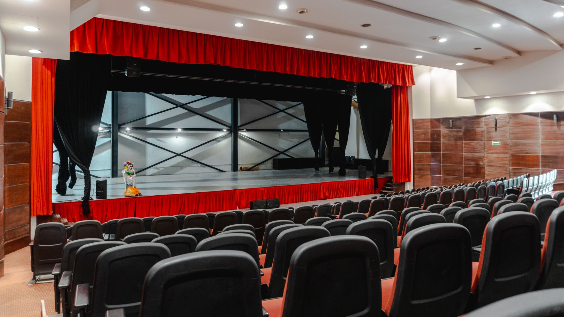 Sala de teatro vacía con butacas y escenario preparado para función